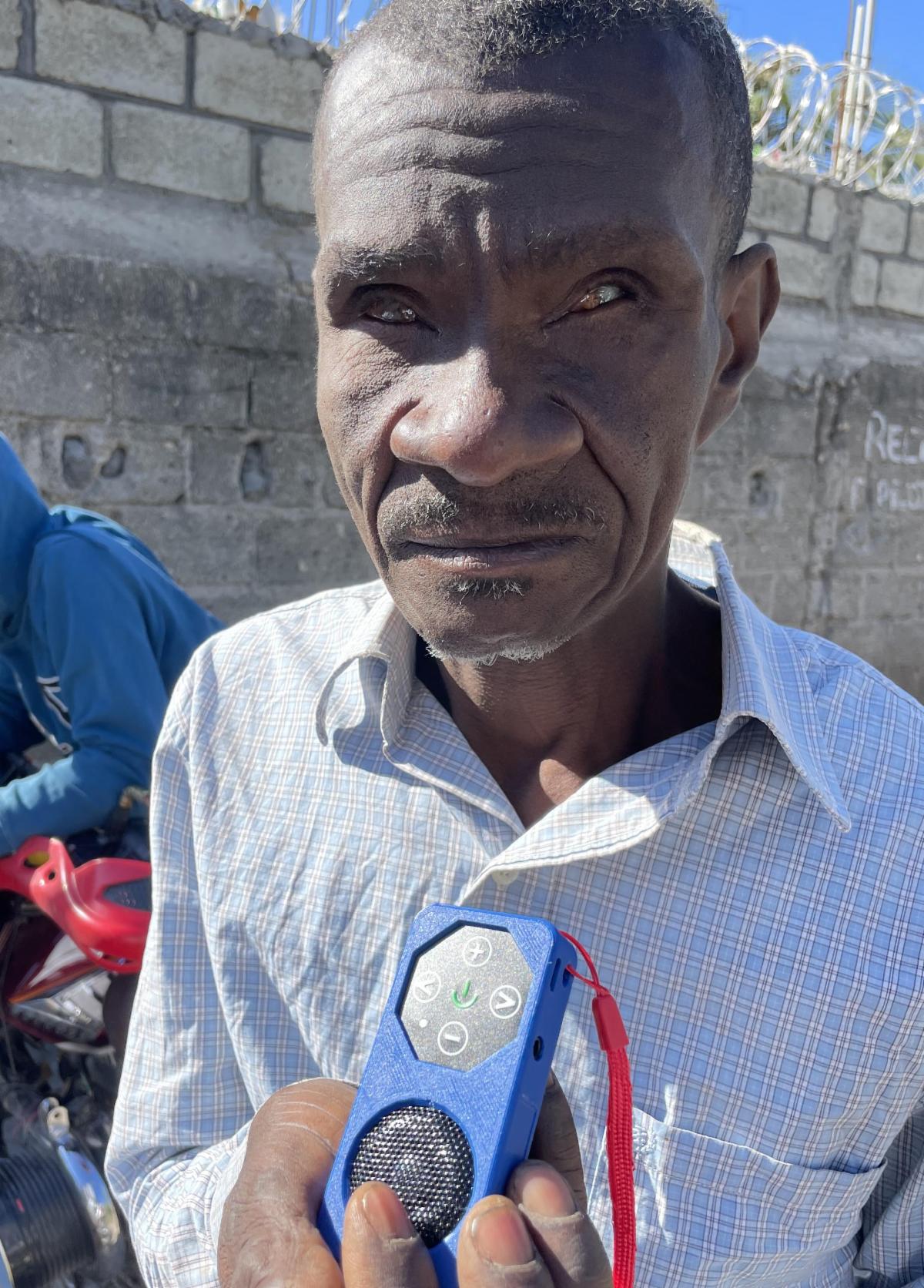 Blind Haitian man holding a SeedPlayer